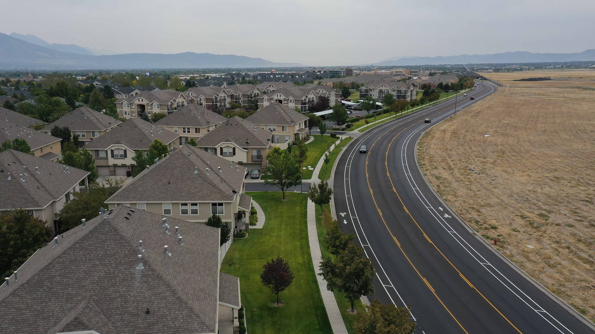 Aerial view of West Jordan homes and rooflines with the mountains beyond